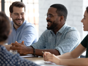 Karriere: Gruppe von Kollegen, die lächelnd in einem Meeting sitzen