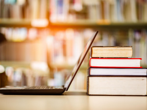 Digitales Archiv: Laptop, der an einem Bücherstapel lehnt