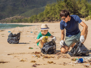 Tonerrücknahme: Vater und Sohn sammeln Müll an einem Strand