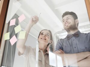 Workflows: Kollegen schreiben auf eine Glaswand